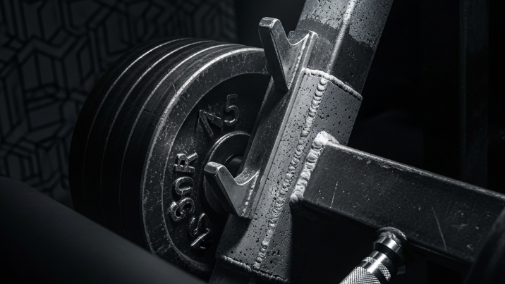 Close-up of a barbell with weight plates on a dark background